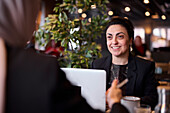 Smiling businesswoman using laptop in cafe