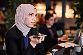 Geschäftsfrau mit Handy in einem Café
