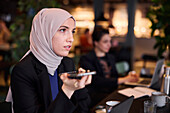 Businesswoman using cell phone in cafe