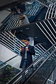 Gutaussehender Mann mit Smartphone und Pappbecher auf der Rolltreppe