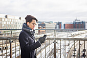 Schöner Mann mit Smartphone auf dem Steg