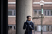 Handsome man with smartphone and paper cup on street