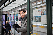 Eleganter Mann mit Smartphone wartet an der Bushaltestelle