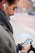 Elegant man with smartphone waiting on bus stop