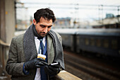 Businessman using phone at train station