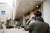 Rear view of man talking on phone in street