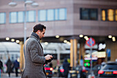Businessman using phone outdoors in city