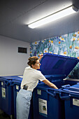 Frau wirft Abfall in die Recyclingtonne