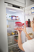 Frau steht vor dem offenen Kühlschrank