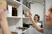 Woman putting standing in front of open cupboard