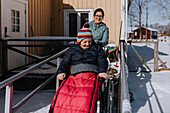 Mutter beim Winterspaziergang mit Tochter im Rollstuhl