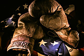 Pair of vintage boxing gloves laying on a flag carefully painted with light