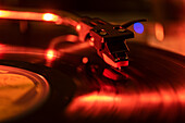 Nahaufnahme einer Plattenspielernadel auf einer Schallplatte im roten Licht