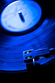 Close-up of a record player needle on record in blue light