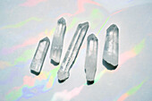 Transparente Quarzkristalle mit Regenbogenlicht im Hintergrund