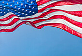 Niedriger Winkel der amerikanischen Flagge weht im Wind gegen den klaren Himmel