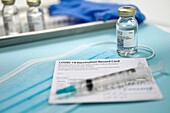Spritze auf Covid-19-Impfpass und Ampullen auf Tablett