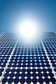 Solar panels with bright sunburst in blue sky