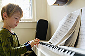 Junge (6-7) spielt Klavier
