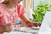 Nahaufnahme einer Frau am Laptop beim Online-Einkauf mit Kreditkarte