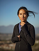Porträt einer nachdenklichen Frau in Sportkleidung, die in einer Landschaft steht
