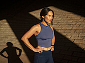 Frau in Sportkleidung in der Nähe einer Mauer im Sonnenlicht