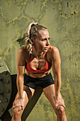 Tired athlete woman leaning against wall