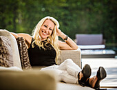 Porträt einer lächelnden blonden Frau auf dem Sofa sitzend