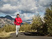 Vereinigte Staaten, Utah, American Fork, Mann joggt auf einer Bergstraße an einem sonnigen Tag