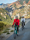 United States, Utah, American Fork, Smiling man and woman riding bicycles on mountain road