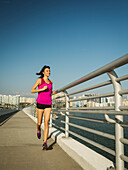 Vereinigte Staaten, Florida, Sarasota, Frau joggt auf Brücke an sonnigem Tag