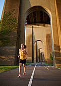Mann joggt unter einer Brücke