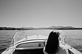United States, New York, Santa Clara, Rear view of woman driving motorboat on Upper Saranac Lake, black and white