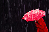 Frau im Schneesturm mit rotem Regenschirm