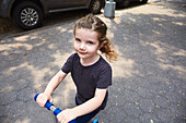 Girl (2-3) riding push scooter on sidewalk