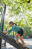 Girl (2-3) climbing slide at playground