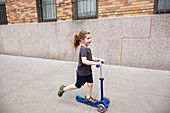 USA, New York, New York City, Girl (2-3) riding push scooter on sidewalk