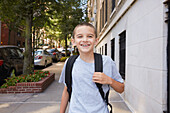 USA, New York, New York City, Portrait of smiling boy (8-9) wearing backpack in city