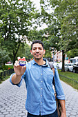 USA, New York, New York City, Porträt eines lächelnden Mannes mit Wahlplakette in der Stadt