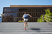 USA, New York, New York City, Rear view of boy (8-9) with backpack running up school steps