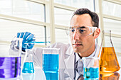 Wissenschaftlerin gießt blaue Flüssigkeit im Labor ein
