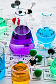 Molecular models and laboratory glassware with liquids on periodic table