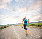 United States, Utah, Cedar Fort, Woman jogging on road in desert landscape