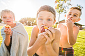 Porträt eines Jungen (8-9) ohne Hemd, der im Garten Pfirsiche isst