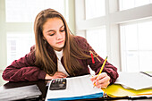 Girl (12-13) doing homework at desk