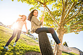 Mädchen (10-11, 12-13) beim Spielen mit der Reifenschaukel im Garten