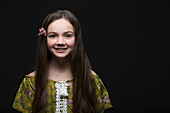 Studio portrait of smiling girl (10-11) in green dress with flower in hair