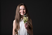 Studio-Porträt eines lächelnden Mädchens (10-11) mit einem Strauß Wildblumen