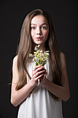 Studio portrait of girl (10-11) holding bunch of wildflowers