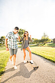 Lächelndes Paar mit Skateboard im Park